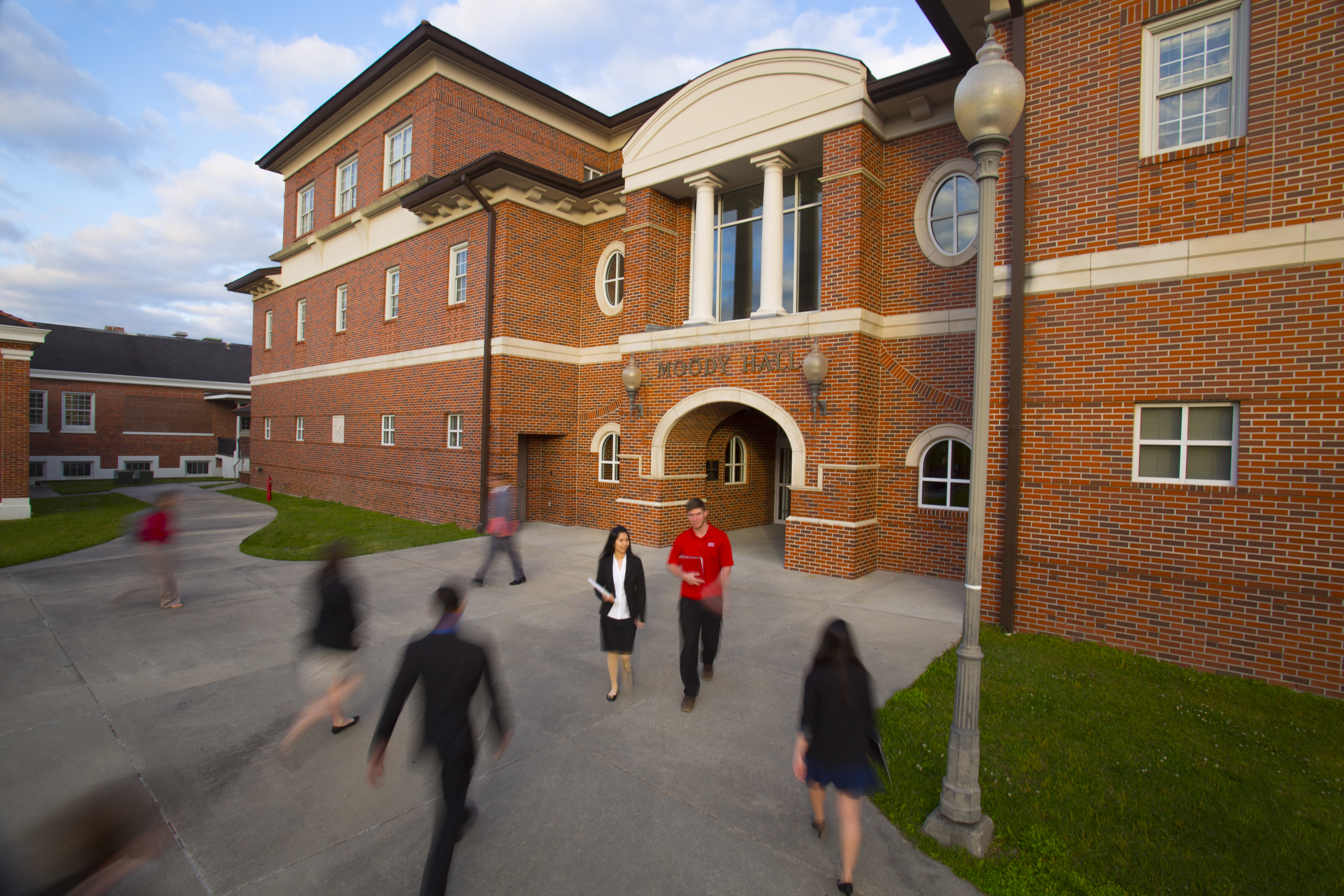 The B.I. Moody III College of Business Administration is pictured in the background as students walk through the foreground.